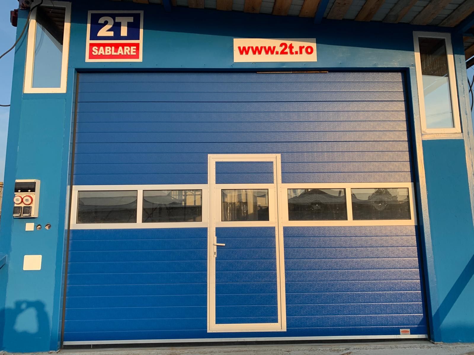 Secție sablare 2T Auto Caracal — ușă atelier cu semnul 2T SABLARE