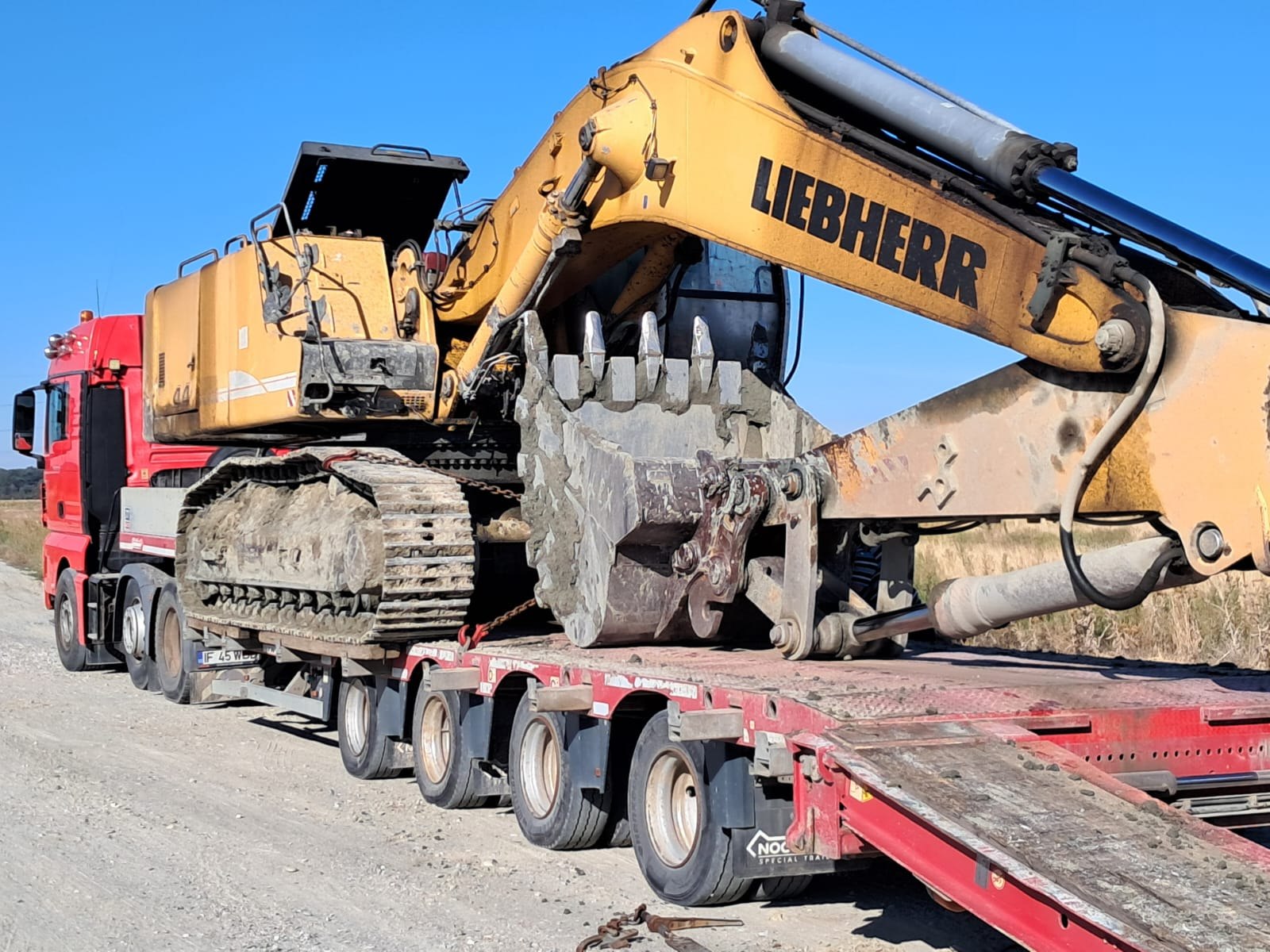 Camion roșu IF 45 cu excavator Liebherr pe lowboy — tractări utilaje Caracal | 2T Auto